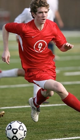 soccer player in red jersey running with ball